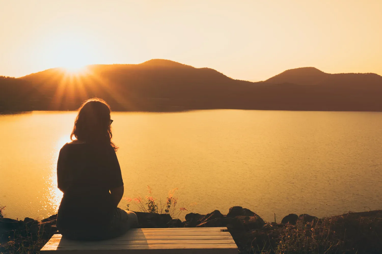 a woman sitting alone watching the sunset